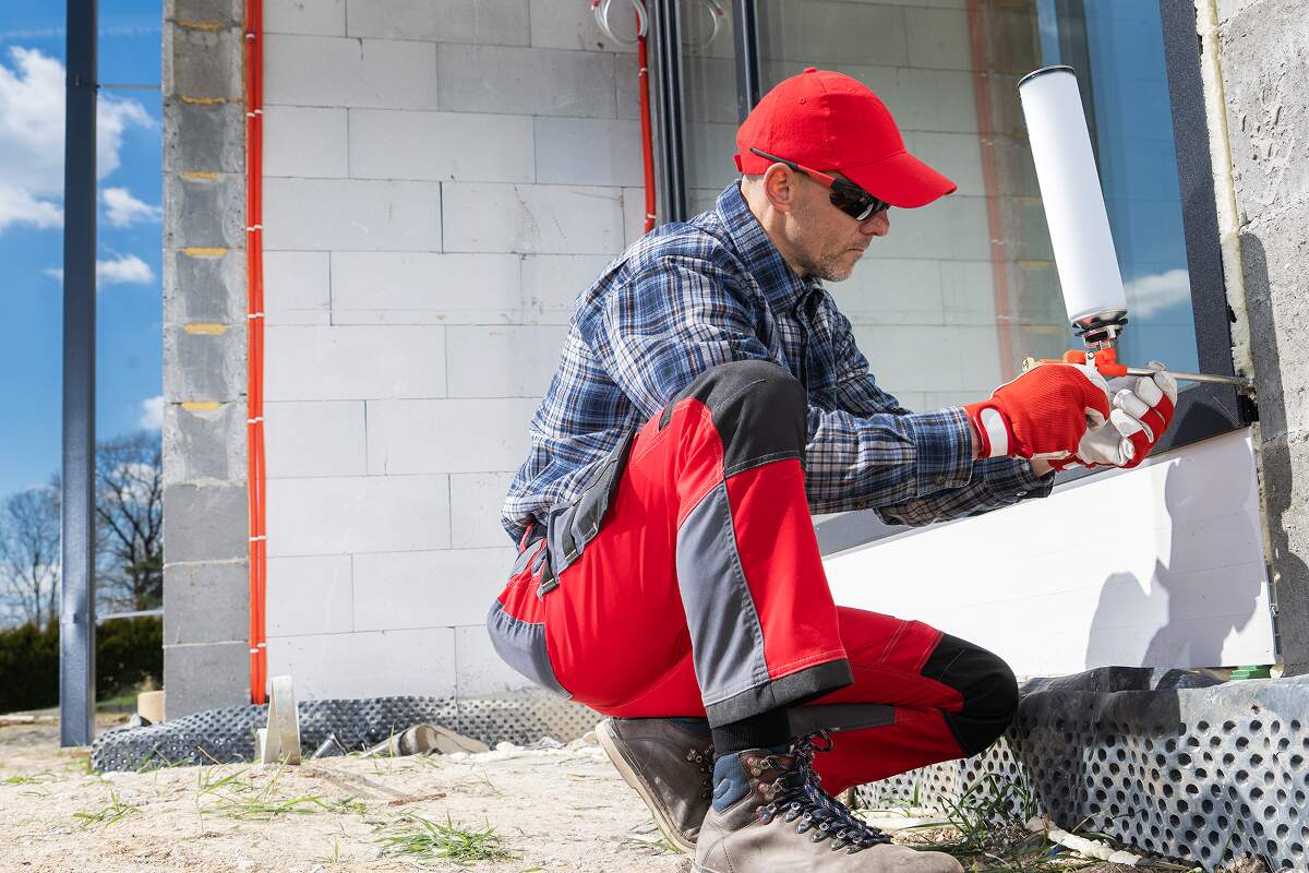construction worker applying sealant on a building RRXT7V6