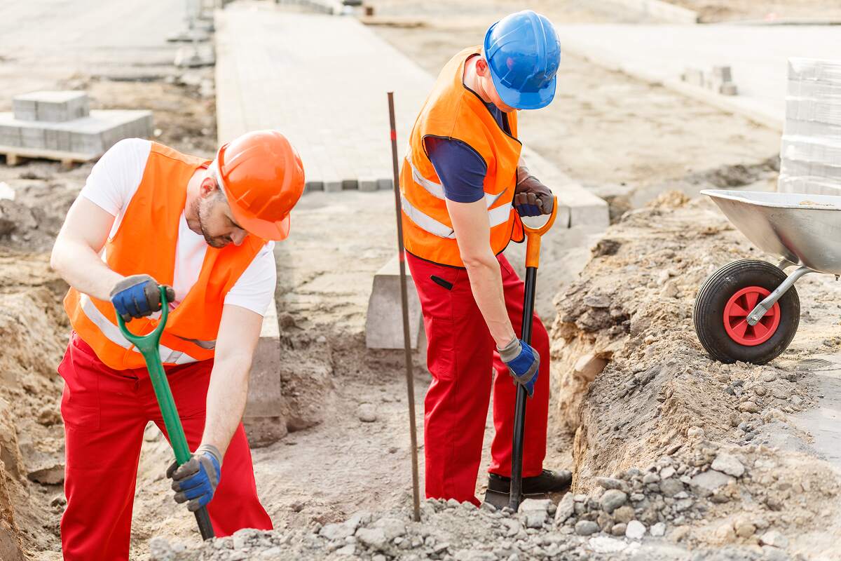 picture of tough workmen pouring sand into barrow 2DWPYP8
